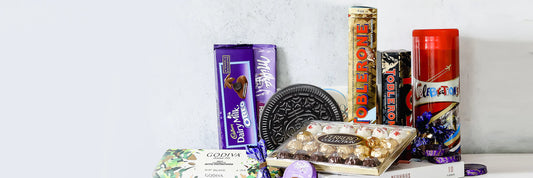 An assortment of various chocolate brands, including Cadbury Dairy Milk, Toblerone, Godiva, Ferrero Rocher, and Oreo, displayed against a white background.
