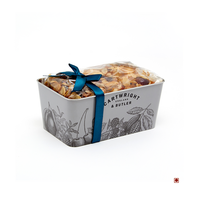 A Cartwright & Butler Cherry & Almond Decorated Loaf Cake Tin 550g with a loaf of almond bread.