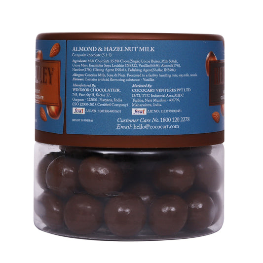Transparent jar filled with Rhine Valley Almond & Hazelnut Milk Dragees 100g, labeled "Californian Almonds & Turkish Hazelnuts milk chocolate" by Shirley.