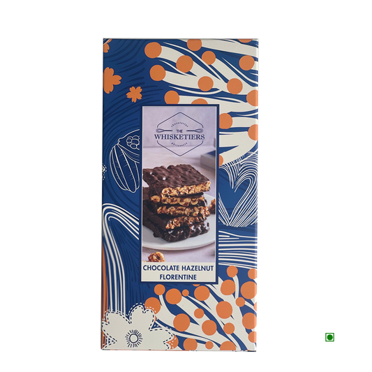 A 100g box of Whisketiers Hazelnut Dark Chocolate, featuring caramelised hazelnuts in dark chocolate with blue, white, and orange abstract packaging.