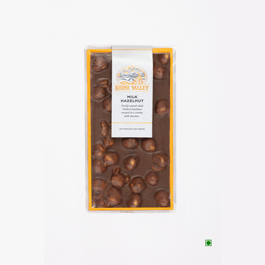 A Rhine Valley Milk Hazelnut 100g bar of chocolate with nuts on it.