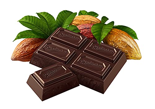 Pieces of Whittakers Dark Ghana Bar 250g chocolate with engraved branding, accompanied by cocoa beans and leaves on a white background.