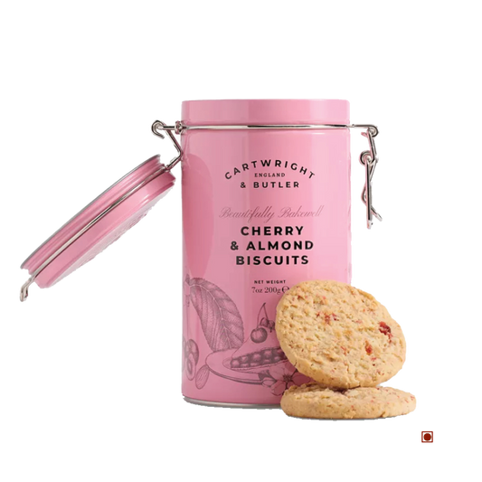 A pink Cartwright & Butler Cherry & Almond Biscuits Tin 200g sits open, with two buttery biscuits featuring ground almonds and glazed cherries displayed beside it on a white background.
