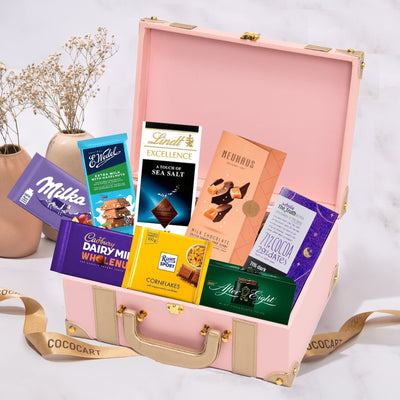 A Gift Hampers suitcase filled with Indulgence Treasure Chest chocolates and ribbons.