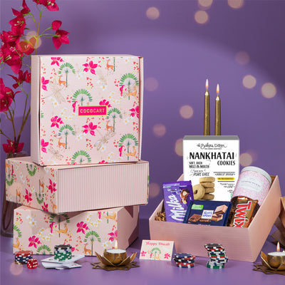 A Festive Delight Pink Opulence Giftbox by Gift Hampers, filled with chocolates and cookies, showcased on a vibrant purple background.