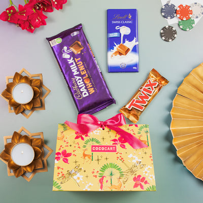 A Rummy Festive Pyramid hamper from Gift Hampers that includes a gift box filled with delectable chocolates and adorned with beautiful flowers, along with a stylish fan.