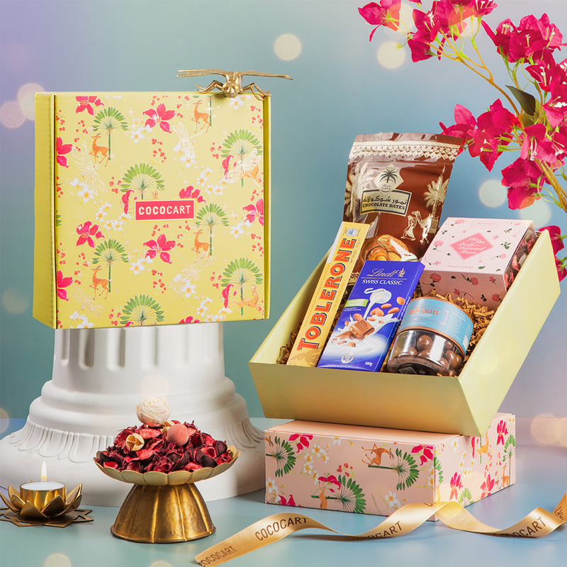 A Gift Hampers Sweet & Scented Festive Green Opulence Giftbox of chocolates and flowers on a table.
