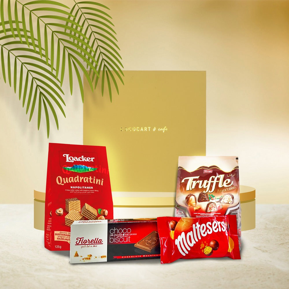 The Indulgence Hamper by Gift Hampers features a selection of chocolates and wafers, including Loacker Napolitaner, Truffle cream chocolates, Fiorella Choco Biscuit, and Maltesers, elegantly displayed in front of a gold gift box.