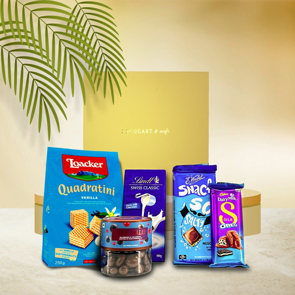 The Box of Happiness Hamper by Gift Hampers elegantly features assorted chocolates and wafers, including delights like Lindt Swiss Classic, Quadratini, Snack So, and the creamy richness of Cadbury Dairy Milk, beautifully displayed in front of a gold gift box.