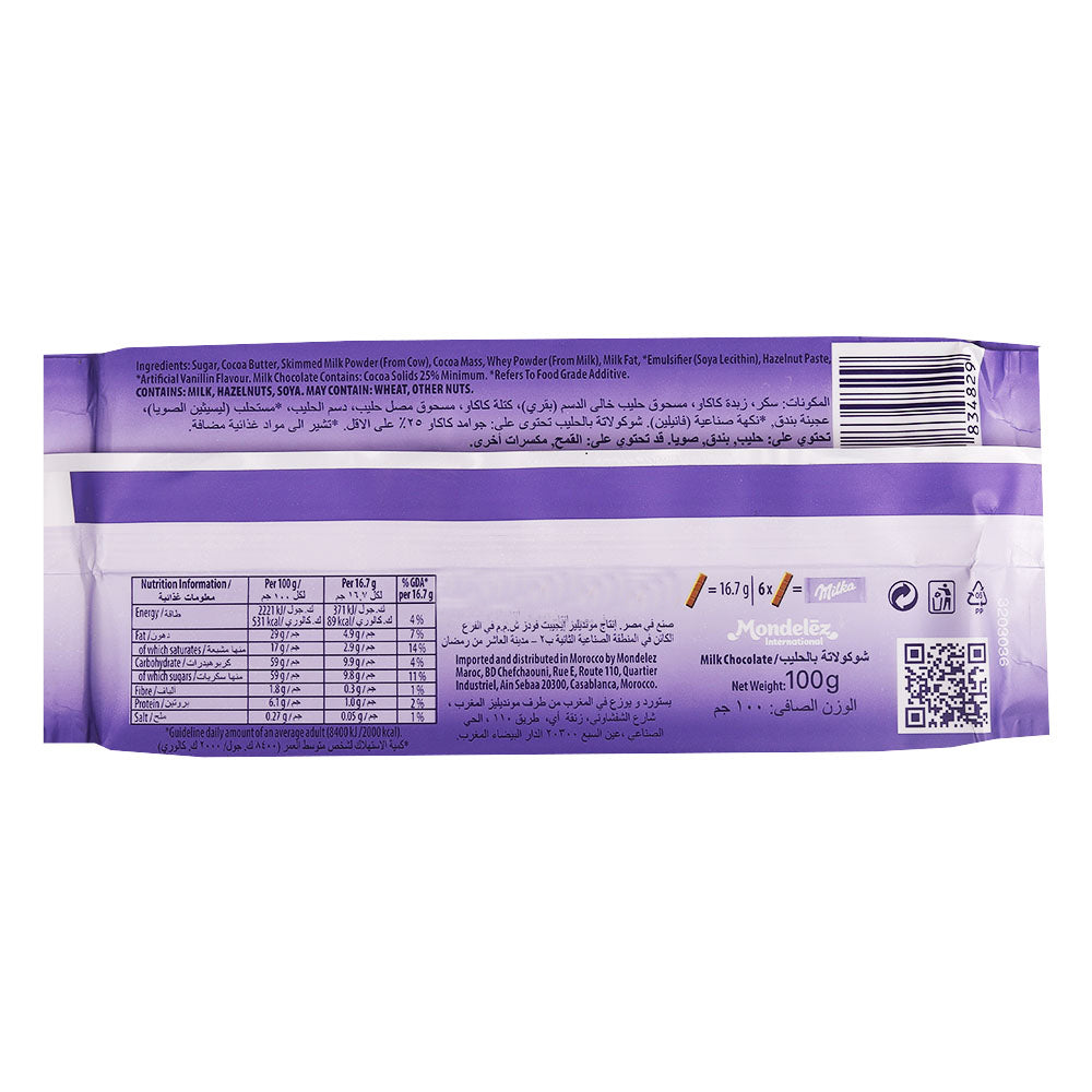 Back view of a purple packaged Milka Alpine Milk Bar 100g with nutritional information, ingredients list, barcode, and various text in English and another language. This product features creamy Alpine milk chocolate in a big size tablet.
