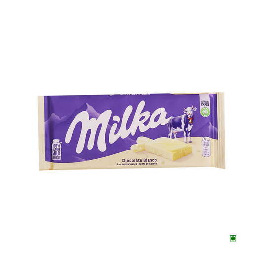A Milka White Bar 100g with a purple and white wrapper, featuring a cow and mountains illustration, made with alpine milk. The label reads "Chocolate Blanco". Originating from GERMANY, it promises a creamy and delightful treat.