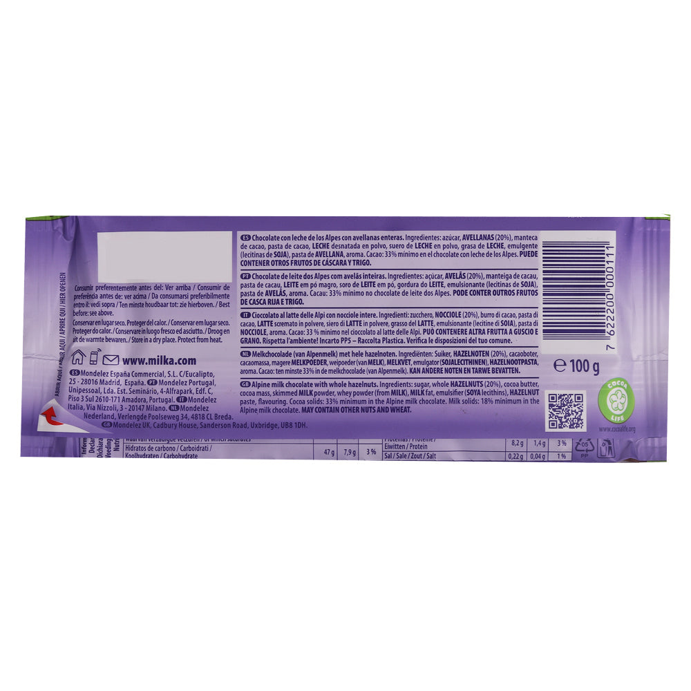 Back of a Milka Broken Hazelnut Milk Bar 100g package showing ingredients, nutritional information, manufacturing details, barcode, and recycling symbols. Packaged in purple wrapping.