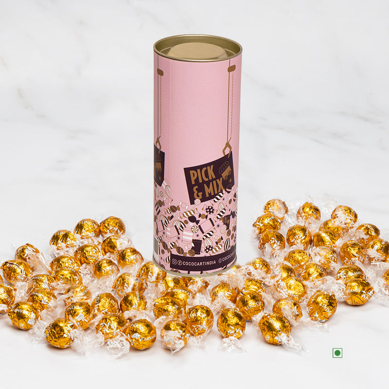 A tin of Pick & Mix : Lindor Caramel 100/250/500g candies on a marble table.