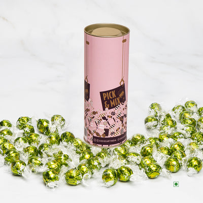 A tin filled with Lindt: Lindor Pistachio 100/250/500g candies on a marble table.