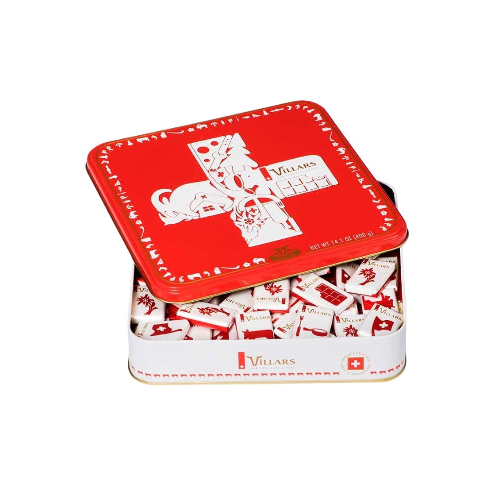 A red and white Villars Milk Napolitains Tin Box 400g, partially open, filled with individually wrapped Swiss milk chocolates. The lid features Switzerland-themed illustrations and the brand name "Villars.