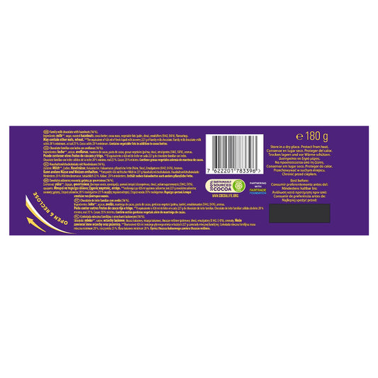 The packaging of the 180g Cadbury Dairy Milk Chocolate With Whole Nuts Bar showcases a vibrant purple background decorated with ingredients, a barcode, and recycling symbols. Indulge in the smooth Cadbury chocolate complemented by the delightful crunch of whole hazelnuts.