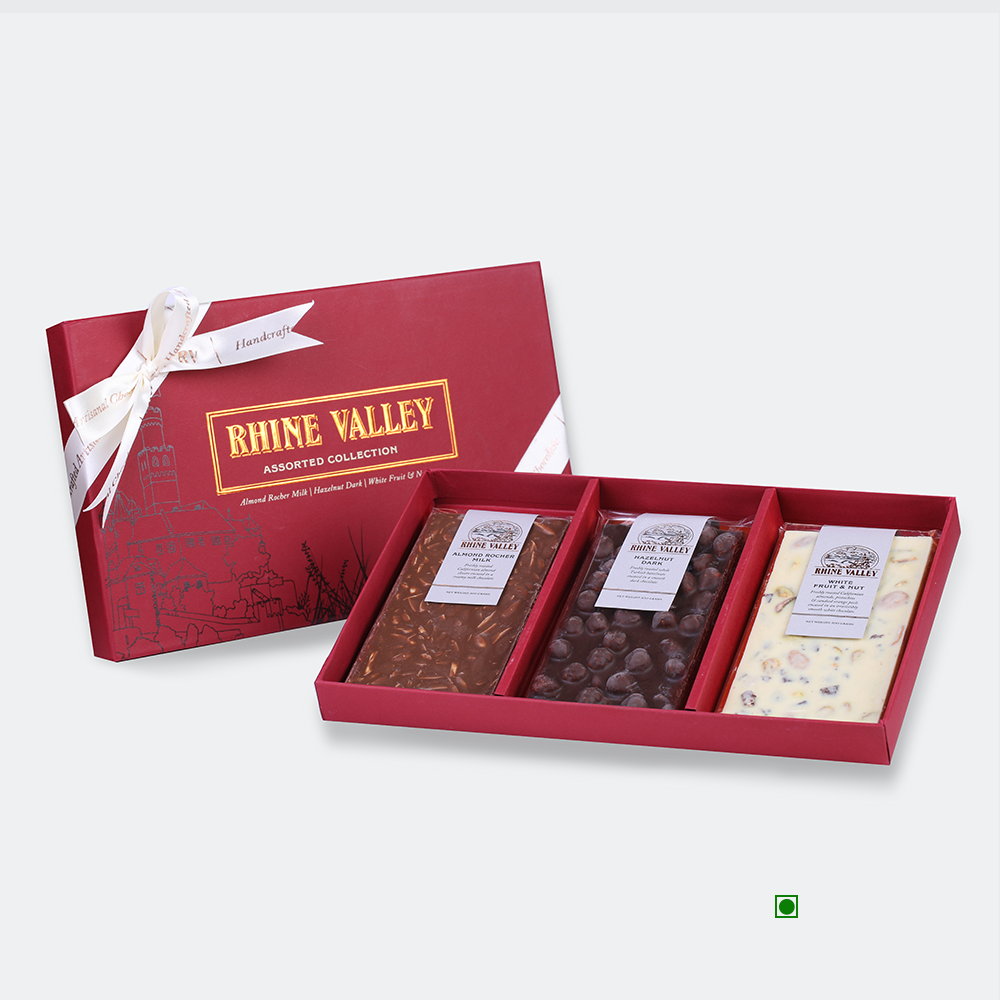 A red box labeled "Rhine Valley Milk, Dark & White Assorted Collection 300g" holds a selection of three delectable bars in various flavors.