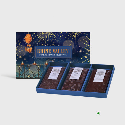 The Rhine Valley Dark Assorted Collection 300g offers a gourmet selection of three chocolate varieties in an open package. The background features a vibrant fireworks illustration, making this gift box by Rhine Valley ideal for any celebration.