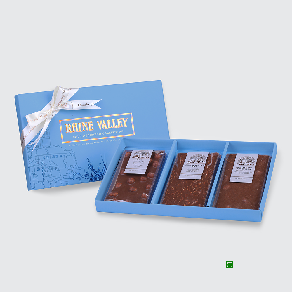 A blue gift box containing the "Rhine Valley Milk Assorted Collection 300g" by Rhine Valley features three gourmet milk chocolate bars. Adorned with a ribbon and decorative design, this open box serves as an ideal assorted chocolate bar gift for any occasion.