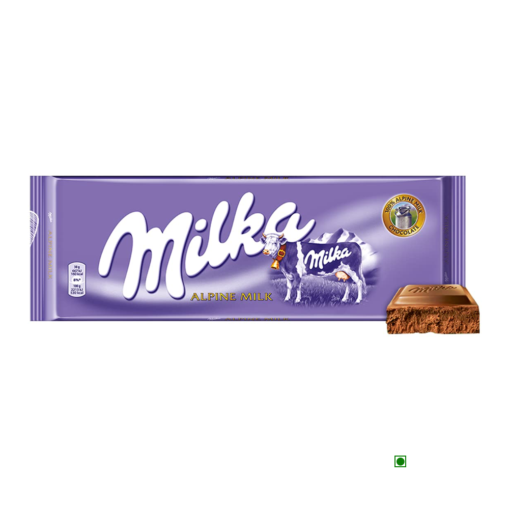 A Milka Alpine Milk Bar 270g with a purple wrapper featuring a cow illustration and an Alpine scene. A small piece of the milk chocolate is shown at the bottom right.