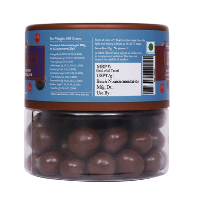 Transparent jar containing Rhine Valley Blueberry & Cranberry Milk Dragees coated in milk chocolate with a product label showing nutritional information and a barcode.