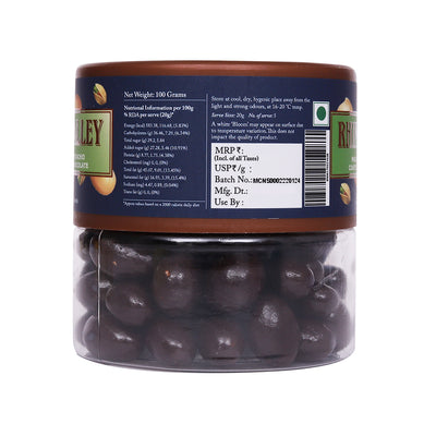 Transparent plastic jar of Rhine Valley brand Rhine Valley Macadamia & Pistachio Dark Dragees 100g, with nutritional and storage information labels visible, and dark chocolate flavoring.