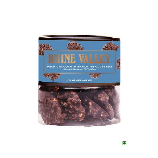 A container of Rhine Valley Milk Chocolate Snacking Clusters 90g with almonds, hazelnuts, and pistachios in creamy milk chocolate. Country of Origin: India. Net weight: 90 grams.