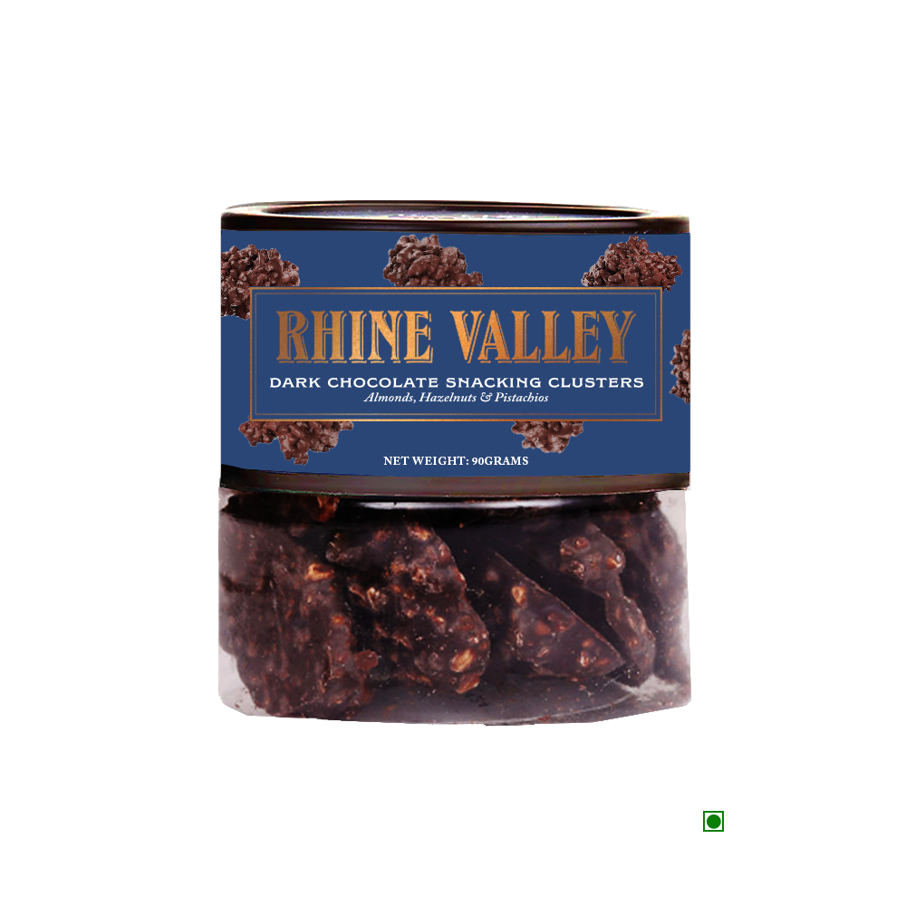 A jar labeled "Rhine Valley Dark Chocolate Snacking Clusters 90g" containing almonds, hazelnuts, and pistachios with a net weight of 90 grams. The transparent jar reveals the tempting dark chocolate clusters inside.