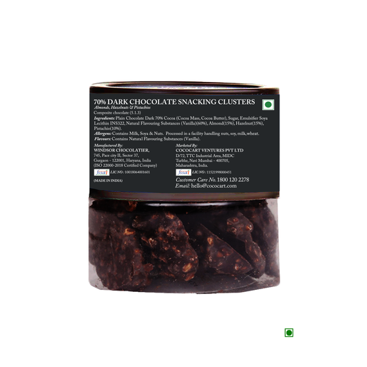 A clear jar with a black label containing Rhine Valley 70% Dark Chocolate Snacking Clusters 90g enriched with crunchy hazelnuts. The label shows ingredients, nutrition facts, and contact information for Cococart Ventures Pvt. Ltd.