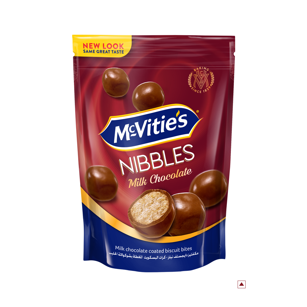 A package of McVitie’s Nibbles Milk Chocolate 110g highlights chocolate-coated biscuit bites with one piece split open to reveal its inner texture. Enjoy the delicious taste that embodies its country of origin, expertly crafted for sweet indulgence.