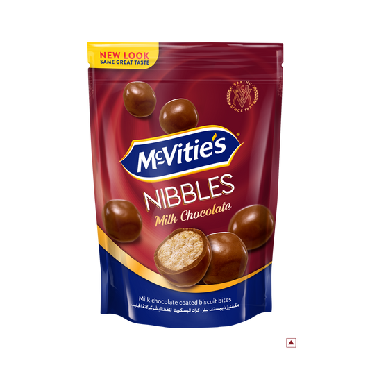 A package of McVitie’s Nibbles Milk Chocolate 110g highlights chocolate-coated biscuit bites with one piece split open to reveal its inner texture. Enjoy the delicious taste that embodies its country of origin, expertly crafted for sweet indulgence.