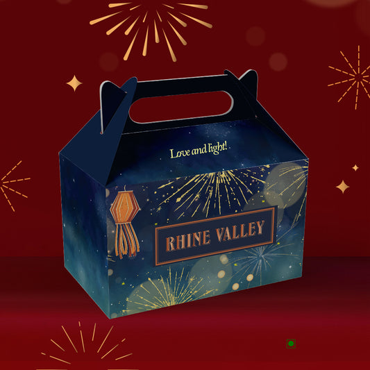 Dark blue festive box titled "Rhine Valley Dragees Collection Box 400g," featuring a fireworks design and the slogan "Love and light!" against a red backdrop. Inside, enjoy the delightful pistachios enveloped in smooth white chocolate, offering a sweet journey from India.