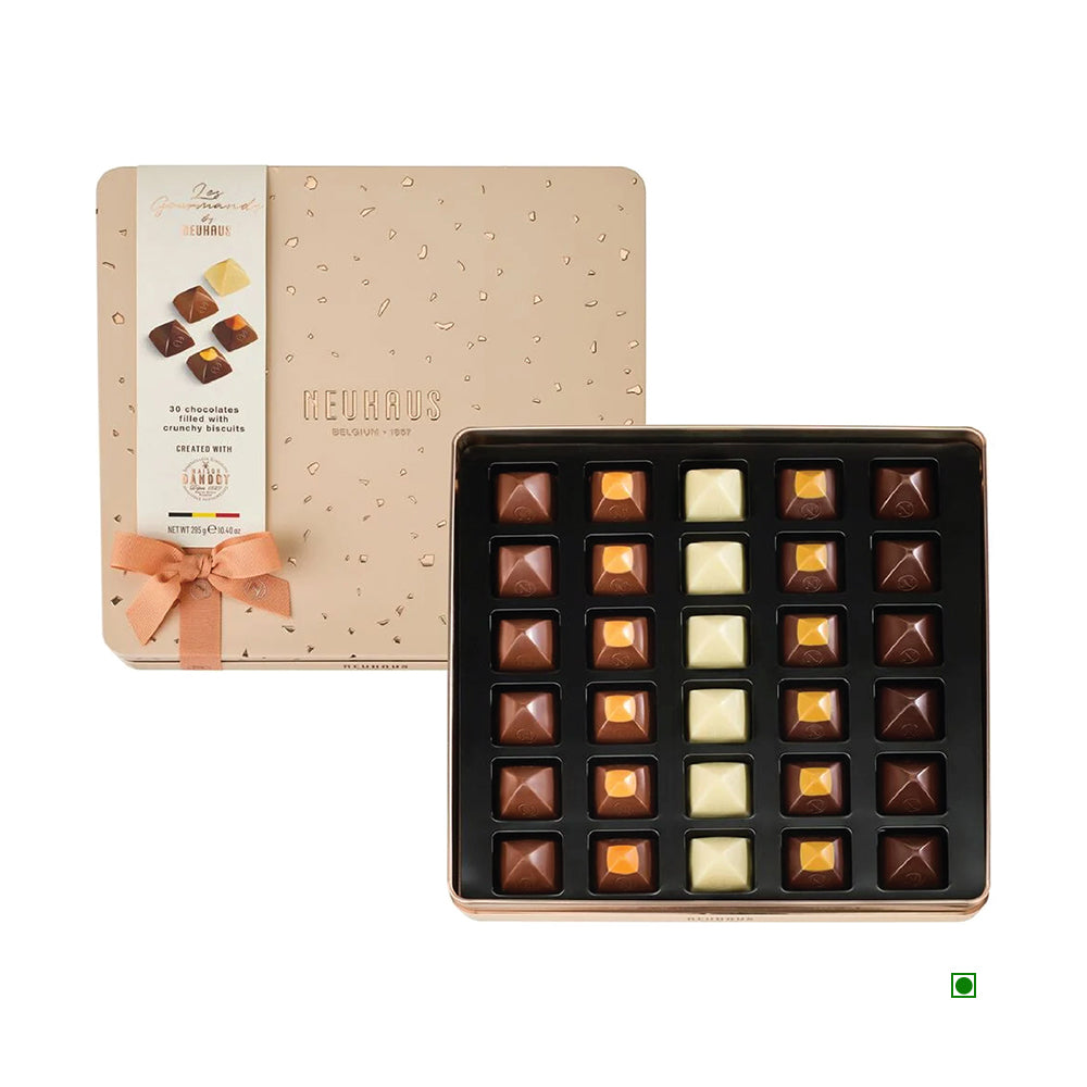 The Neuhaus Les Gourmands offers a selection of 30 gourmet chocolates in an elegant tin box, complete with a bow, showcasing a variety of assorted pieces in different colors.