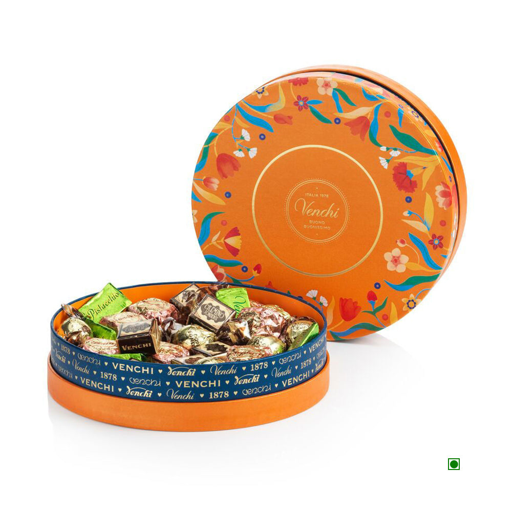 The Venchi Murrine Medium Hamper 400g, an open round tin inspired by Baroque artistry, features assorted wrapped chocolates and a blue Venchi-branded ribbon around the edge.