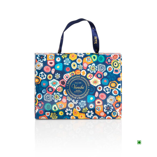 The Venchi Murrine Gift Bag 150g is a colorful tote with floral and geometric patterns from the Murrine Collection, featuring "Venchi" branding. Crafted by skilled Venetian artisans for added elegance.