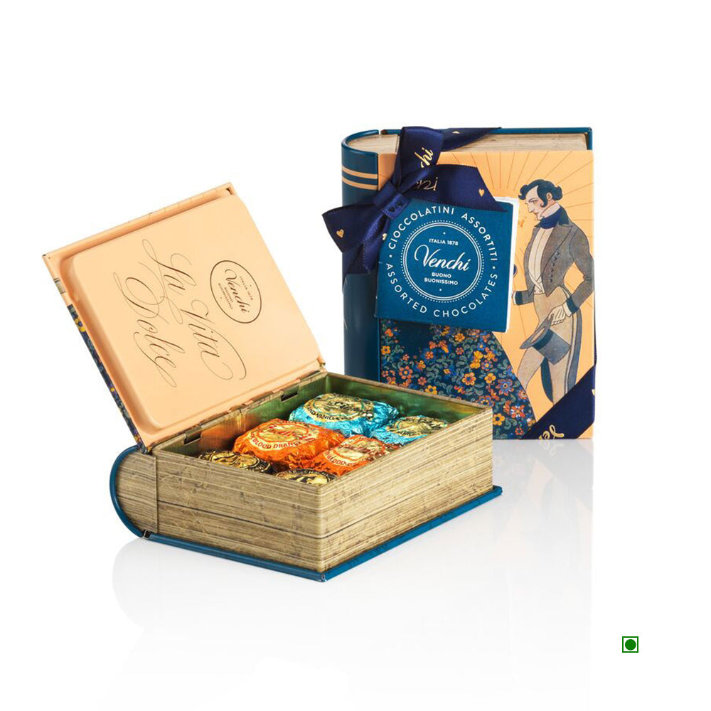 The Venchi Vintage Mini Book Pack 119g is a decorative book-shaped box made in Italy, partially open to reveal assorted wrapped chocolates. It features an illustrated cover and a ribbon.