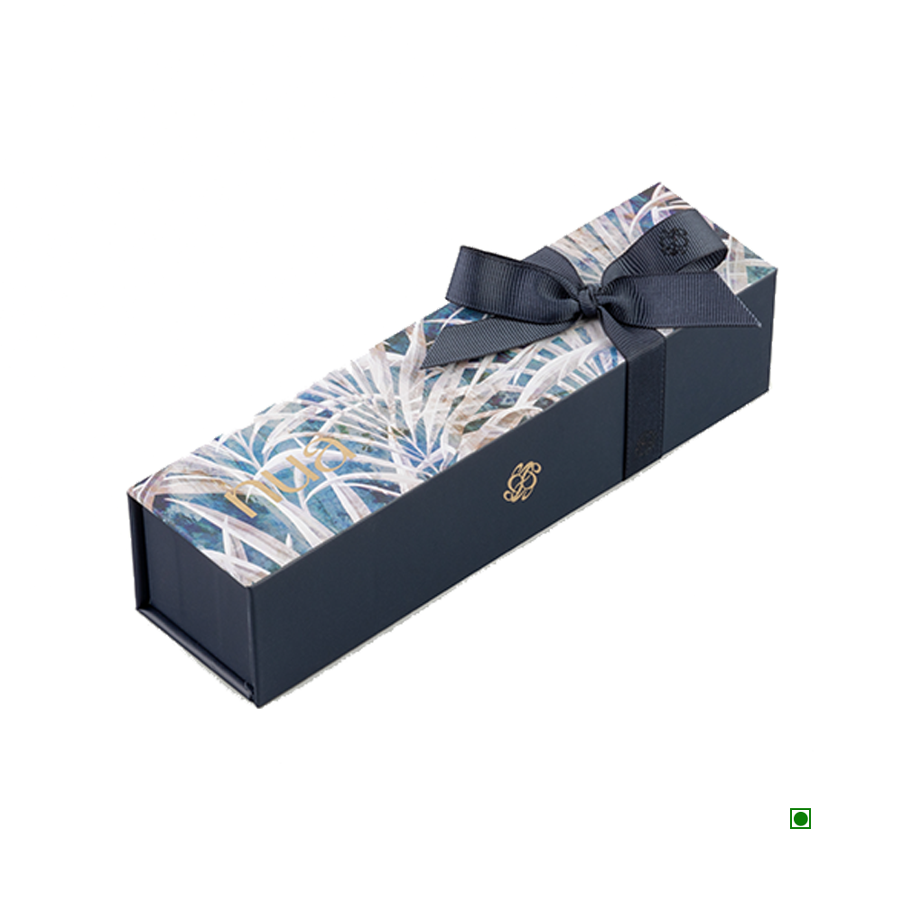 The Nua Small Gift Box White Fronds 100g, adorned with a botanical design on the lid and tied with a black ribbon, evokes the elegance of Saudi Arabia's desert blooms.