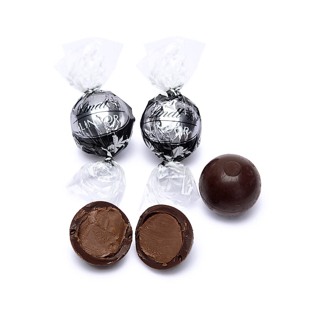 Two wrapped Lindt Pick & Mix: Lindor Extra Dark 250/500g truffles, one unwrapped whole truffle, and two unwrapped truffle halves with visible luscious chocolate filling tempt the senses.