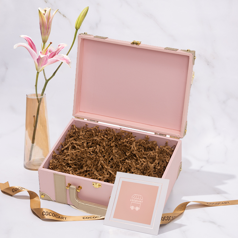 A Build your own Blush Pink Trunk suitcase with a pink lily next to it. (Brand: Gift Hampers)