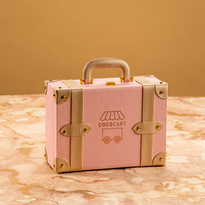 A Build your own Blush Pink Trunk sitting on a marble table.