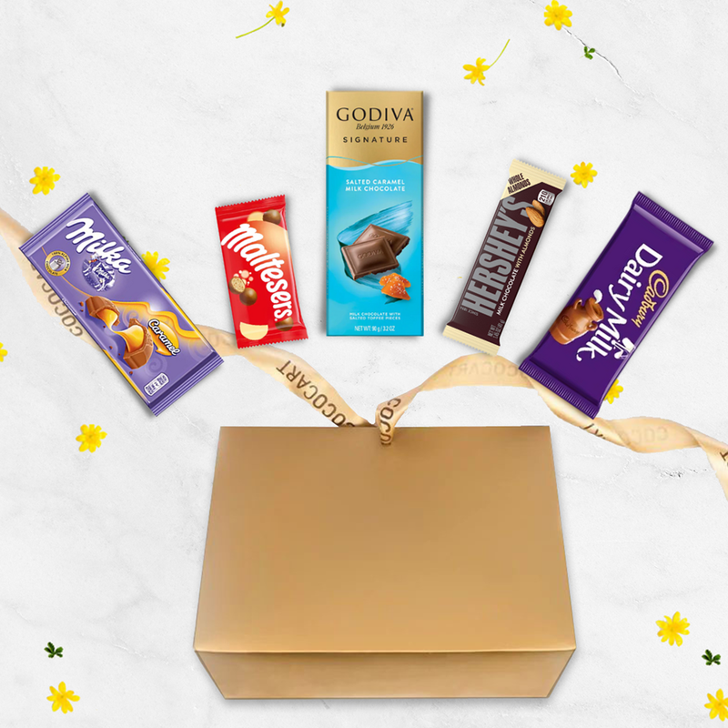A Gift Hampers gold gift box filled with The Ultimate Chocolate Experience (Eggless) and flowers.