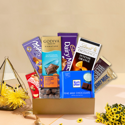 A Gift Hampers gold box filled with The Ultimate Chocolate Experience and flowers.