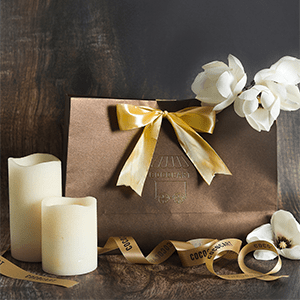 A brown Gift Bag with candles and a ribbon.