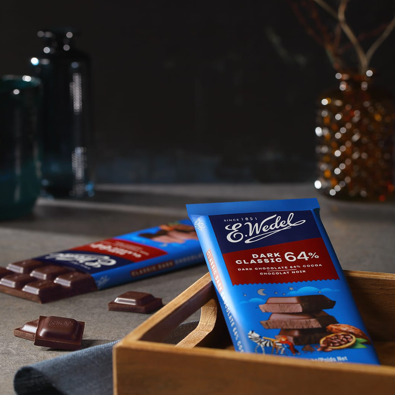 A Wedel Dark 64% Cocoa Chocolate Bar 90g sitting on top of a wooden tray.