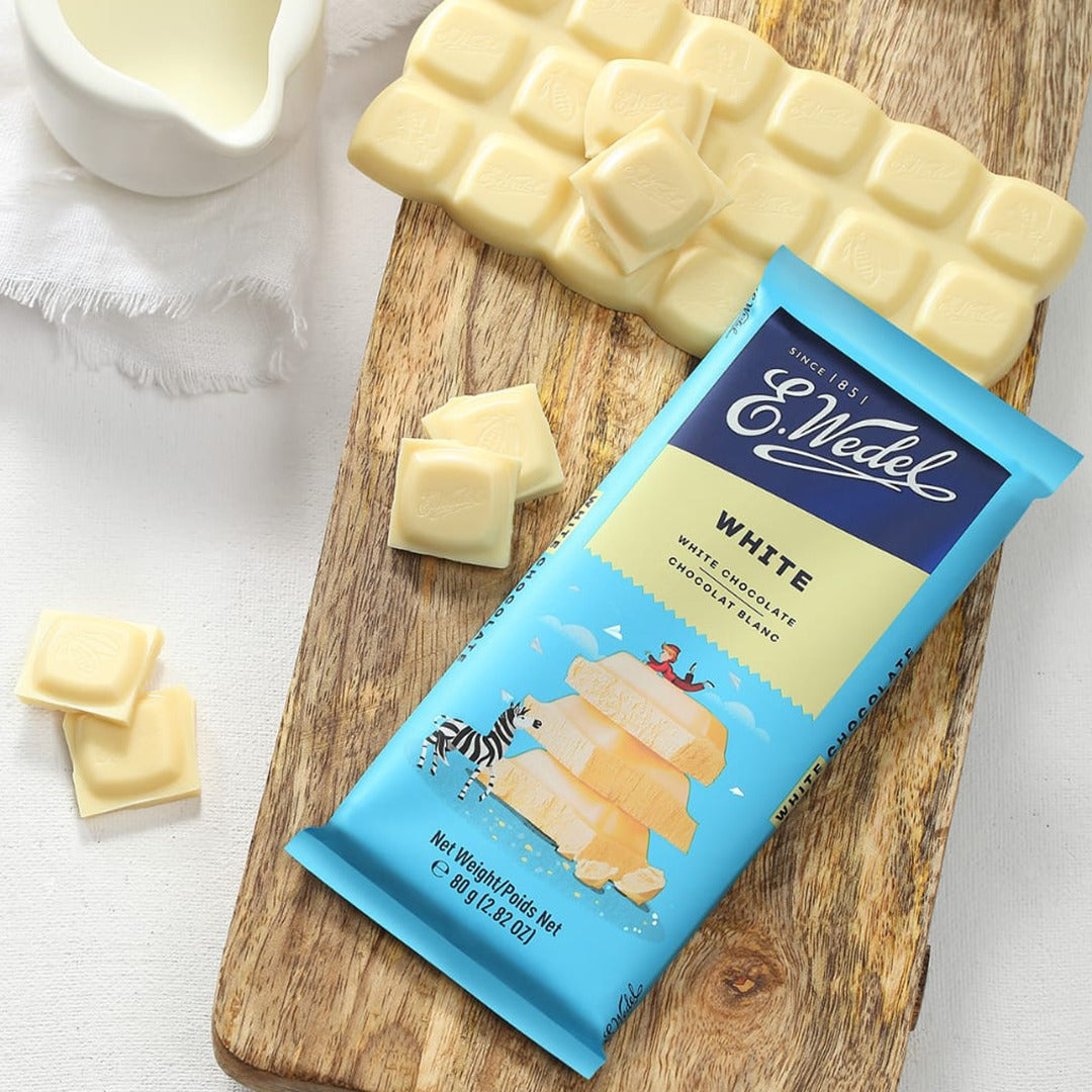 A Wedel White Chocolate Bar 80g sitting on a cutting board.