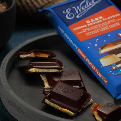 Elvis' Wedel Dark Chocolate With Creme Brulee Filling Bar 100g on a plate next to a bowl.
