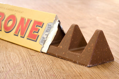 A Toblerone Milk Chocolate Bar 200g is sitting on top of a wooden table.