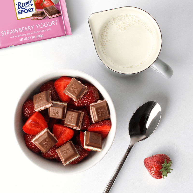 A bowl of Ritter Sport Strawberry Yoghurt Bar 100g with strawberries and chocolate.