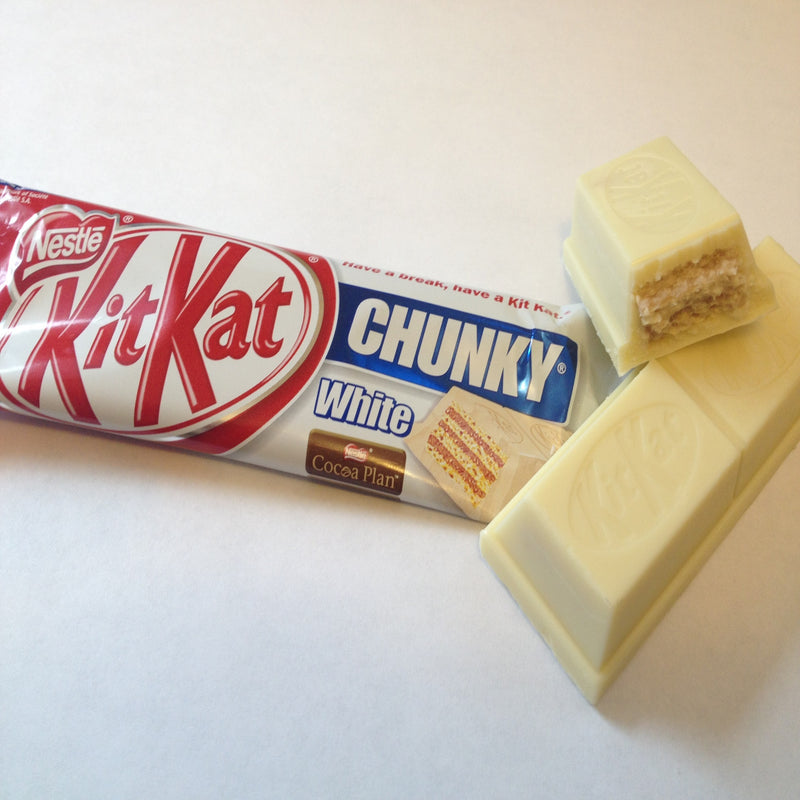 A Kit Kat Chunky White 40gm chocolate bar partially unwrapped with a piece broken off, exposing the crunchy wafers inside.