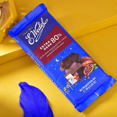 A Wedel Extra Dark 80% Cocoa Chocolate Bar 80g sitting next to a feather.